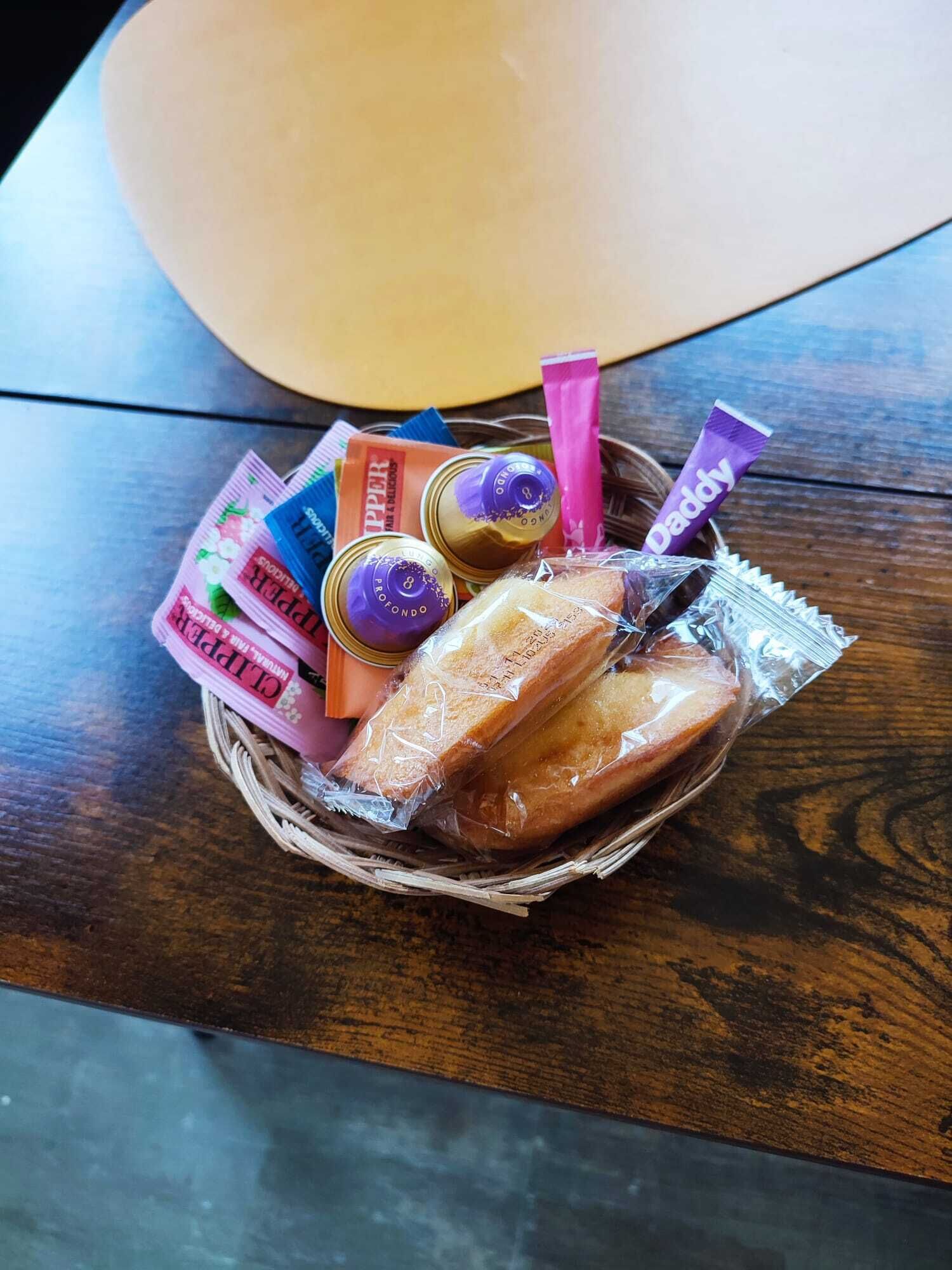 A basket containing various food items and a tube of toothpaste on a wooden table.
