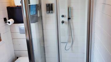 Une cabine de douche fermée par des parois en verre, avec des toilettes et un porte-serviettes, dans une salle de bain moderne.