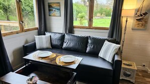 Ein modernes Wohnzimmer mit einem schwarzen Ledersofa, einem Holztisch und einem Esstisch für zwei Personen.