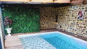 Ein Pool mit Steinmauer und einer grünen Hecke.