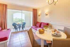 Ein Hotelzimmer mit Balkon, ein Esstisch gedeckt mit Tellern, Gläsern und einer Obstkorb.