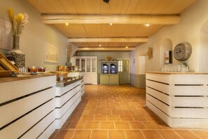A kitchen with a brick floor, wooden ceiling beams, and a counter with jars and a vase. - Riverfront Retreat Near Cannes (Mallemort)