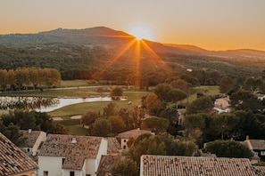 A residential area with houses, a golf course, and a hill in the background.