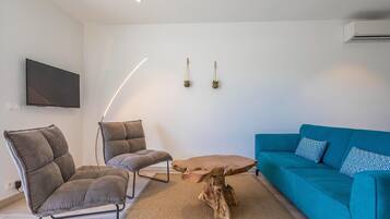 A modern living room with a sofa, two chairs, a coffee table, a TV, and wall-mounted plants.