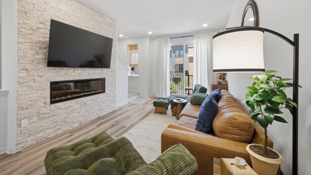 Ein Wohnzimmer mit Steinwand, Flachbildfernseher, einer Couch, einem Couchtisch und einem Blumentopf.
