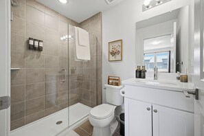 A modern bathroom with a shower, toilet, and sink. - Luxury 2 BR townhome with EV charging (Detroit)