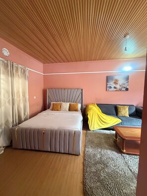 Ein Schlafzimmer mit Bett, Sofa, Couchtisch, einem Gemälde und einem Deckenventilator.