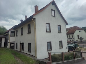 Un bâtiment à deux étages, doté de nombreuses fenêtres, d’une cheminée bien visible et d’une petite enseigne au rez-de-chaussée.