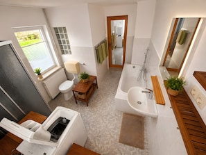 Une salle de bain moderne équipée de toilettes, d’un lavabo, d’une douche et d’un lave-linge encastré.