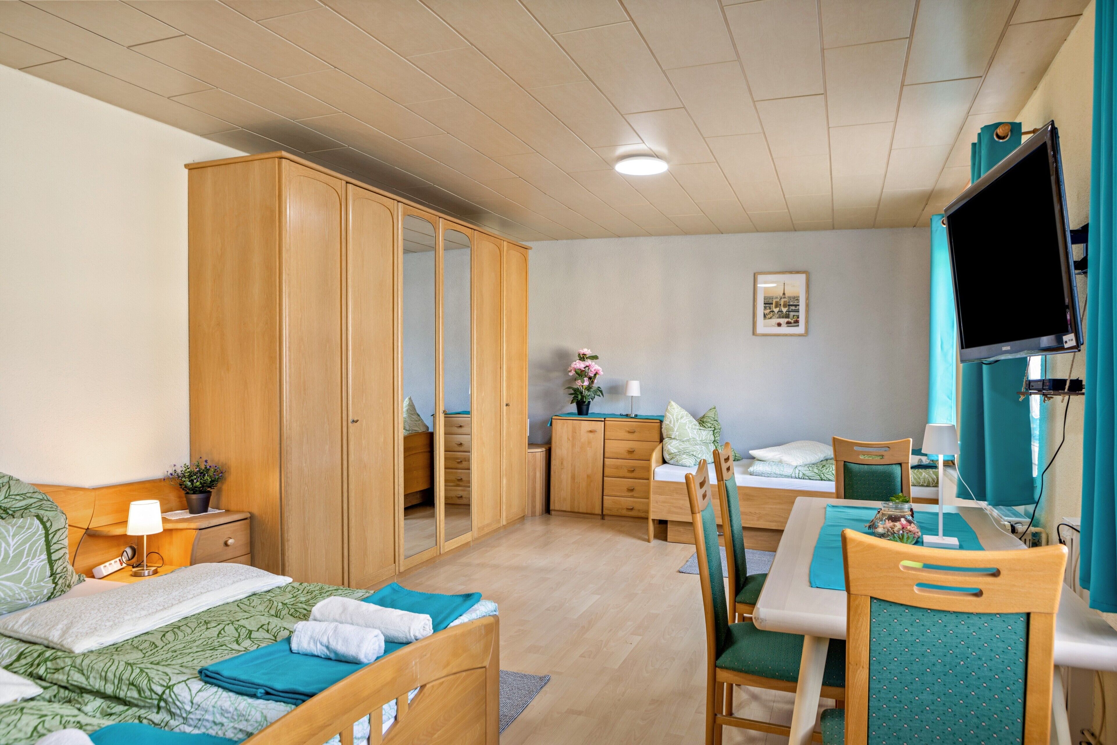 Ein Schlafzimmer mit einem Bett, einem Schreibtisch, einem Stuhl, einem Kleiderschrank und einem Fernseher.