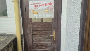 A wooden door with a sign above it, a yellow pipe to the left, and a metal grate at the bottom.