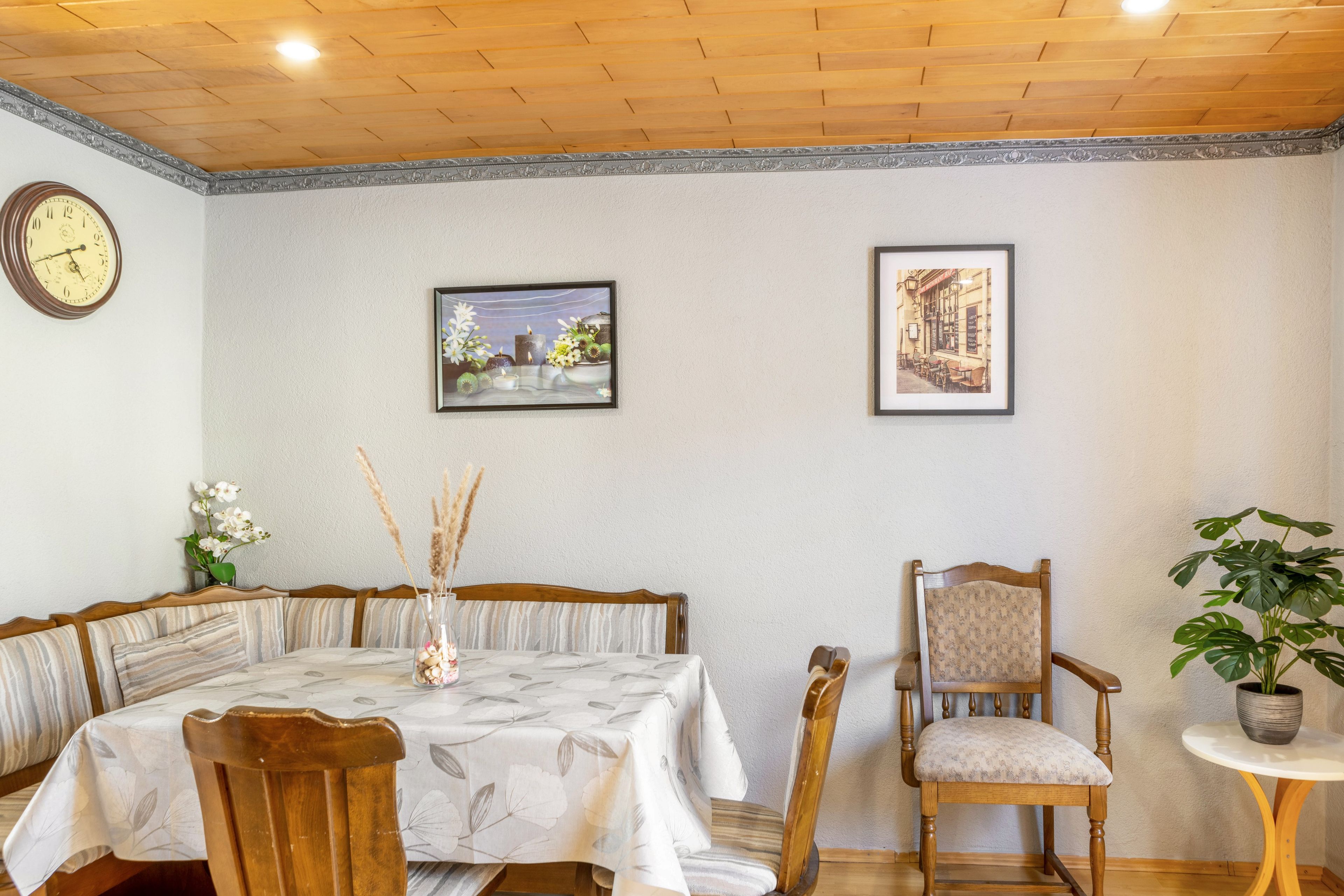 Ein Essbereich mit einem Holztisch, Stühlen, einer Uhr und zwei gerahmten Bildern an der Wand.