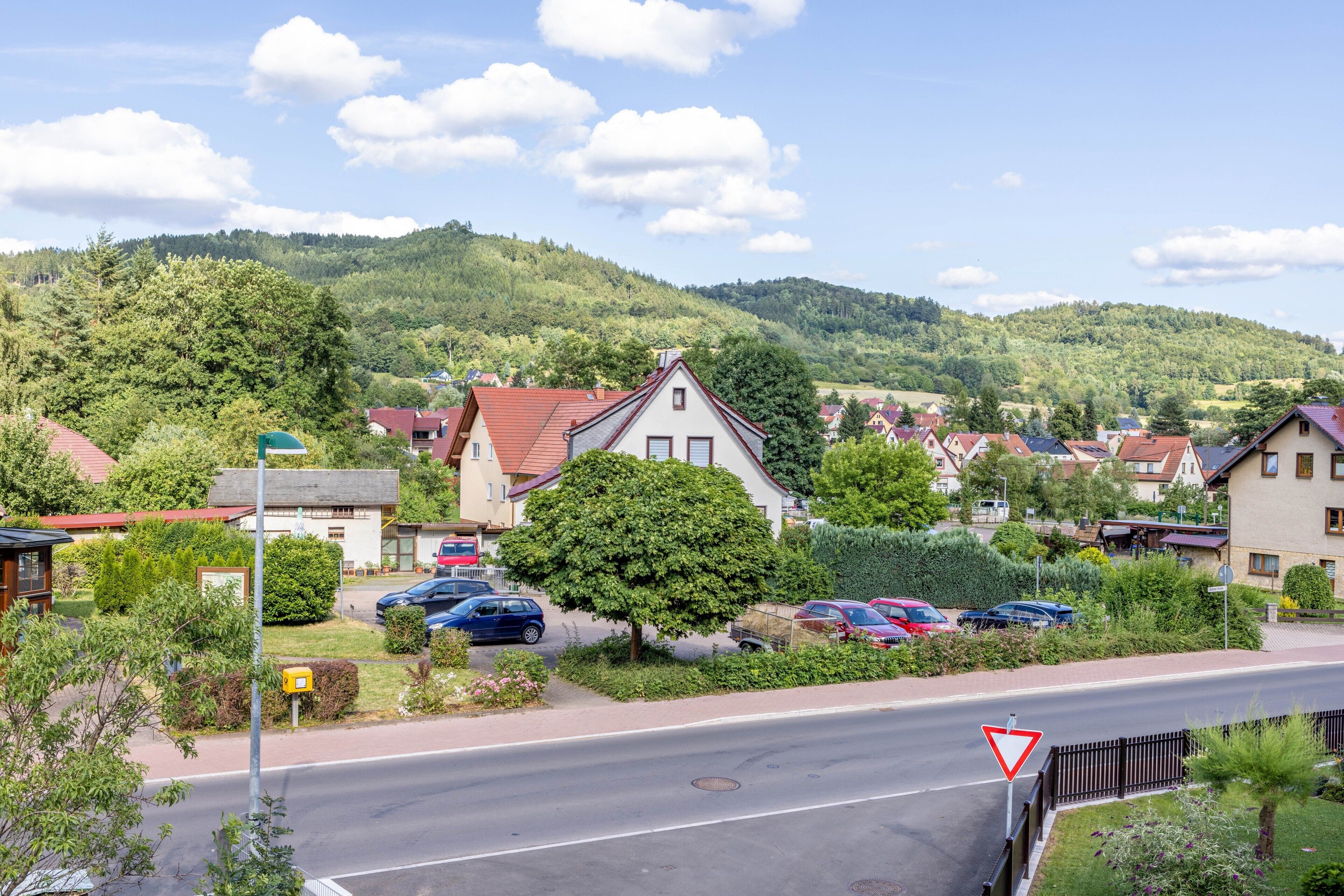 Ein Wohngebiet mit Häusern, parkenden Autos und einer Straße mit einem Vorfahrtsschild.