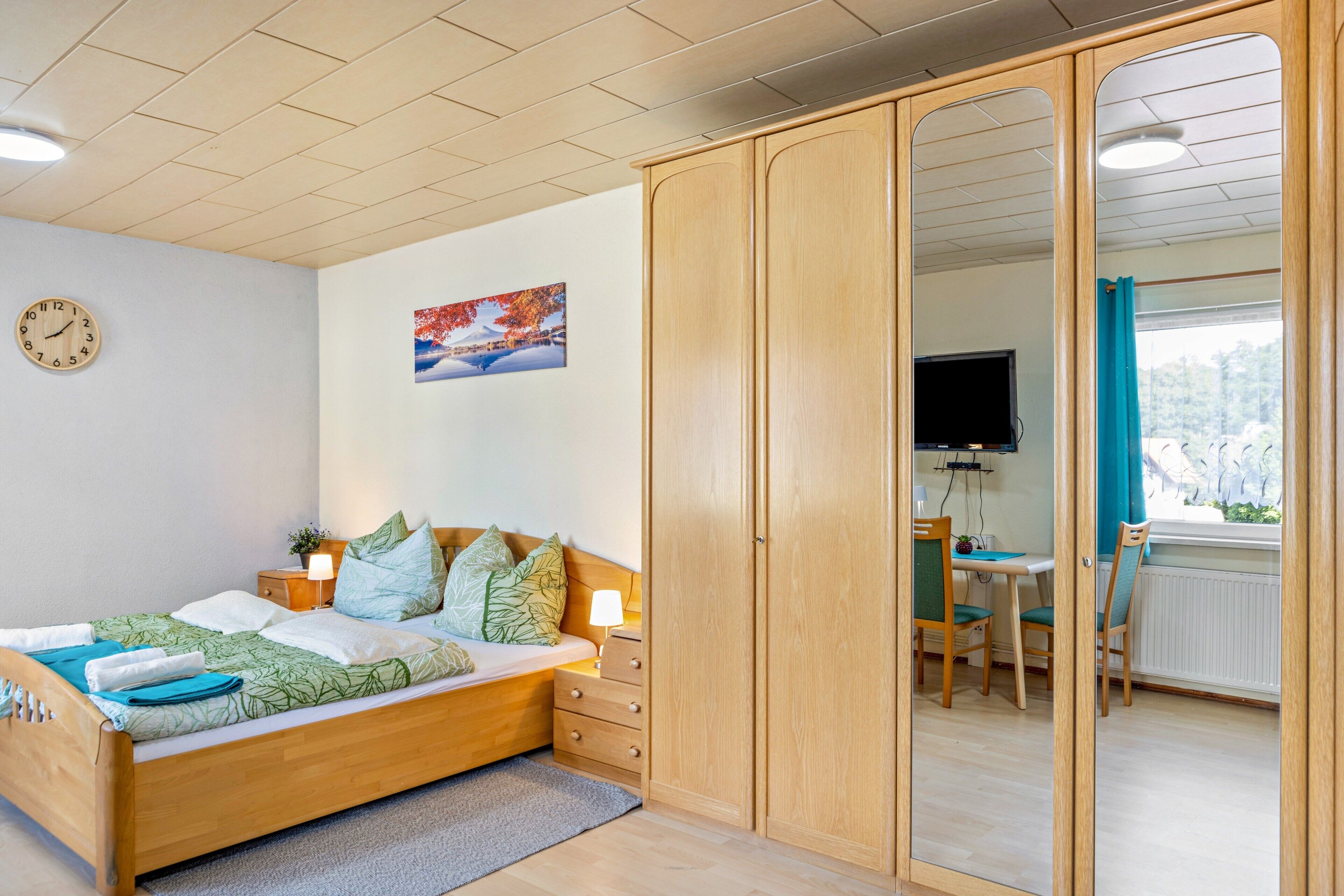 Ein Schlafzimmer mit einem hölzernen Bett, einem Nachttisch, einer Lampe, einer Uhr, einem Gemälde und einem Kleiderschrank.