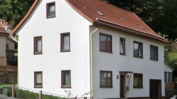 A two-story building with a red-tiled roof, multiple windows, and a brick base.