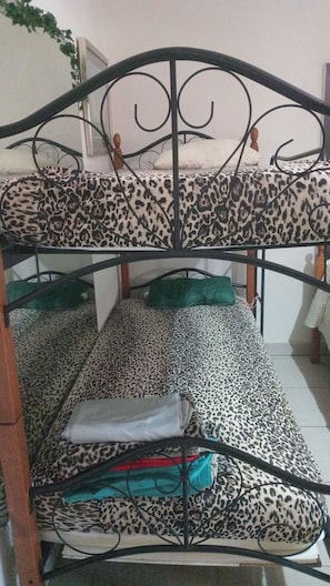 A bunk bed with leopard print bedding, a wooden headboard, and a green pillow. - WEAVING MILL ARUBA HOSTEL bed and coffee (Oranjestad)