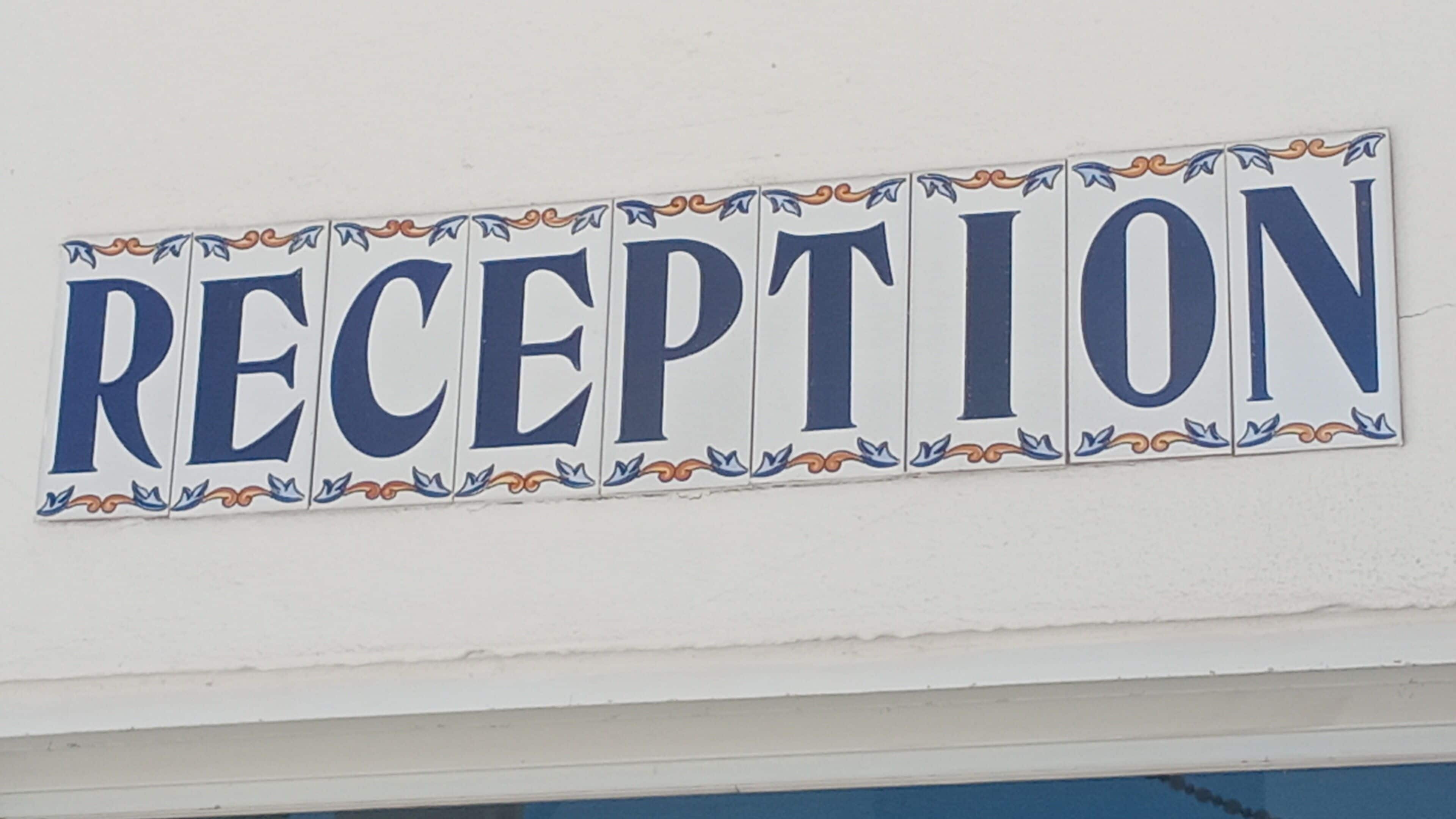 A sign with the word 'RECEPTION' in large blue letters, surrounded by decorative borders.