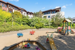 A playground with sand, play structures, and toy cars.