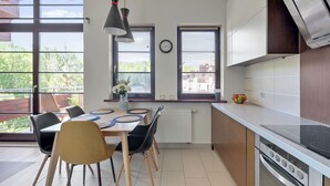 Une cuisine moderne avec un coin repas, de grandes fenêtres et une vue sur l’extérieur.