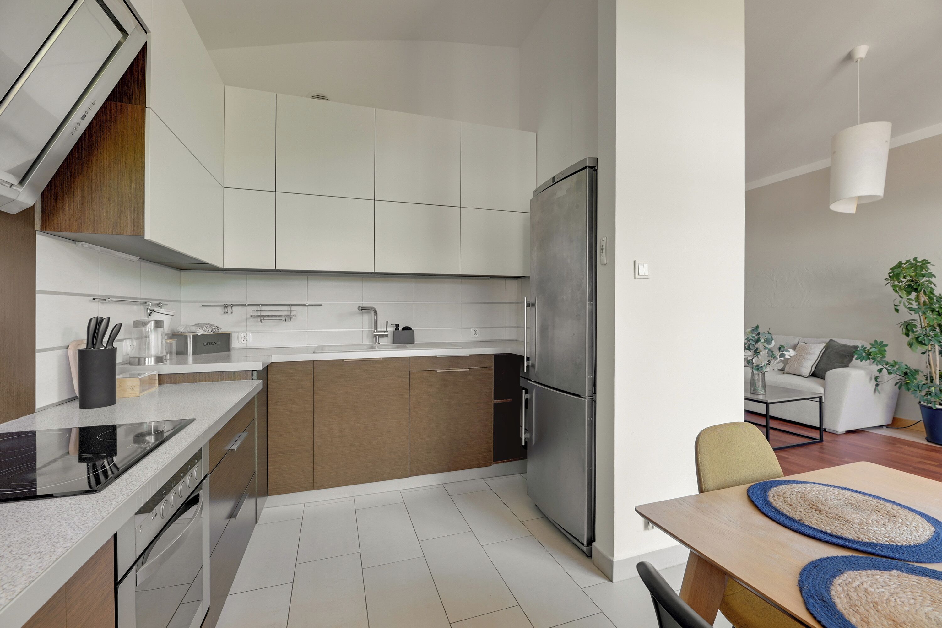 Una cocina moderna con horno integrado, un refrigerador y una zona de comedor con mesa y sillas.