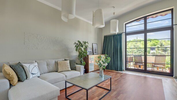 Un salon comprenant un canapé, une table basse et une grande fenêtre donnant sur un paysage verdoyant.