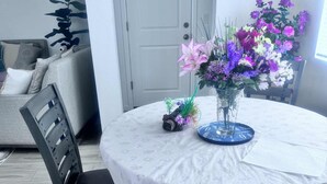 A round dining table with a white tablecloth, a vase with flowers, and a chair. - Upscale Aurora Suite • Quiet, Private & Stylish (Aurora)
