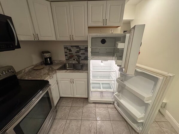 A kitchen with white cabinets, a stainless steel sink, a coffee maker, and a built-in oven.
