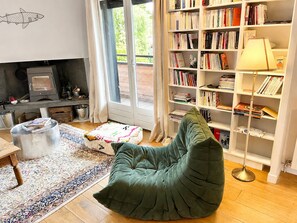 A cozy living room with a green bean bag chair, a bookshelf, a fireplace, and a large window. - Charming apartment between lake and mountains in Sevrier (Sevrier)