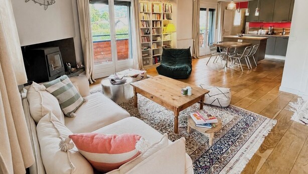 Een gezellige woonkamer met een bank, een salontafel, een boekenkast en een open haard.