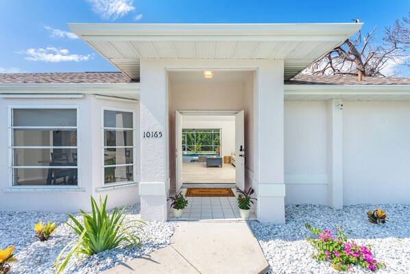 A modern house with a number "10165" on the wall, a covered porch, and a view into the interior. - Beachside Getaway Minutes from the Gulf - Heated Pool - Sleeps 8 (Englewood)