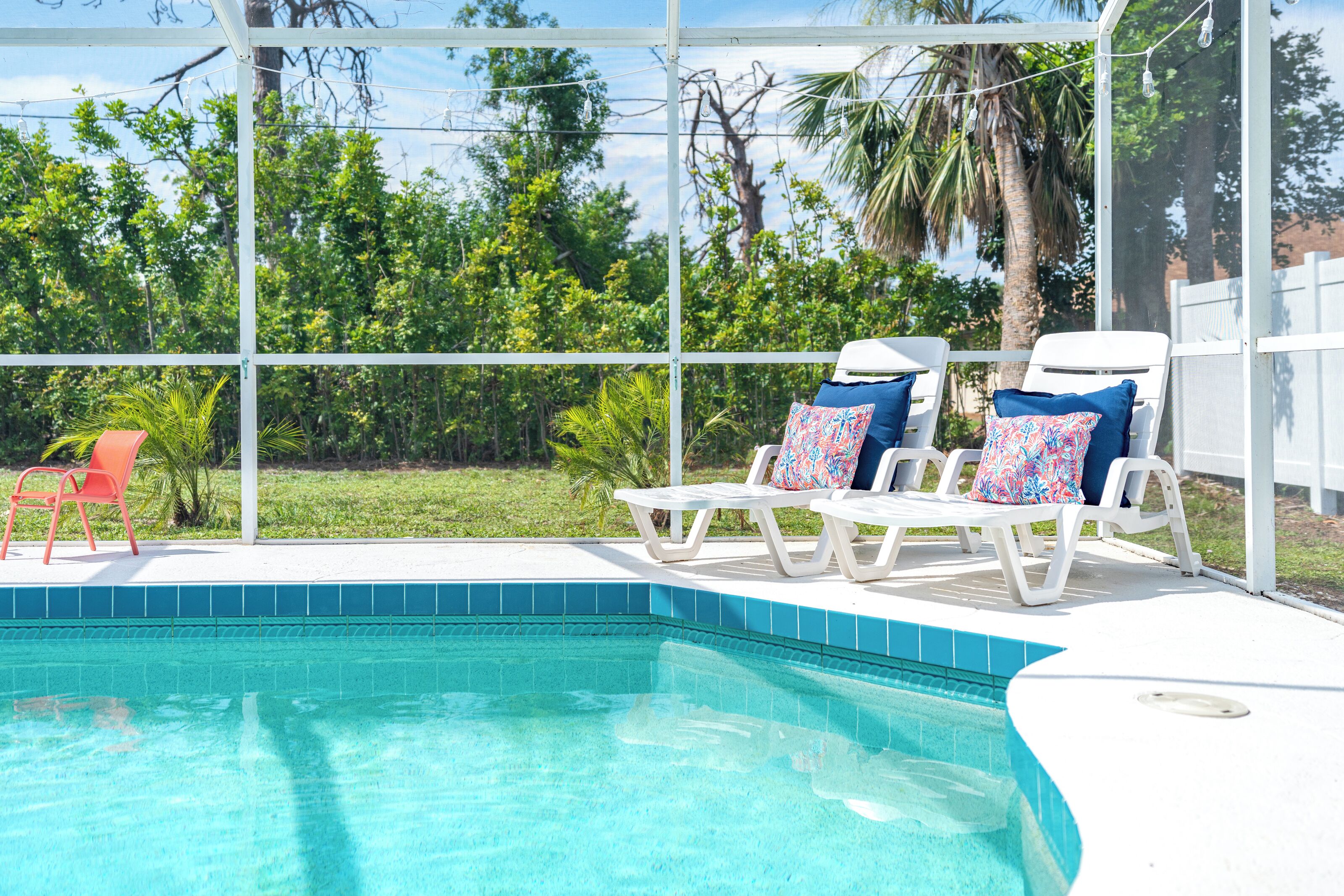 A pool area with a clear view of the surrounding greenery and a fenced enclosure.