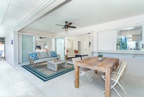 A spacious living area with a wooden table and wicker chairs, a sofa with patterned cushions, and a ceiling fan. - Beachside Getaway Minutes from the Gulf - Heated Pool - Sleeps 8 (Englewood)