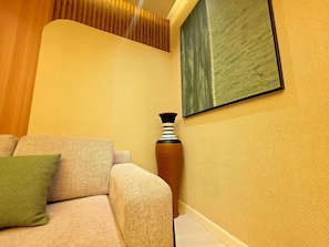 A room with a sofa, a vase, and a painting on the wall. - Amazonia Luxury  (Abuja)
