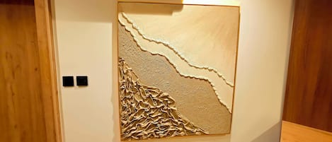 A room with a textured wall art piece, a wooden door, and a white air conditioning unit.