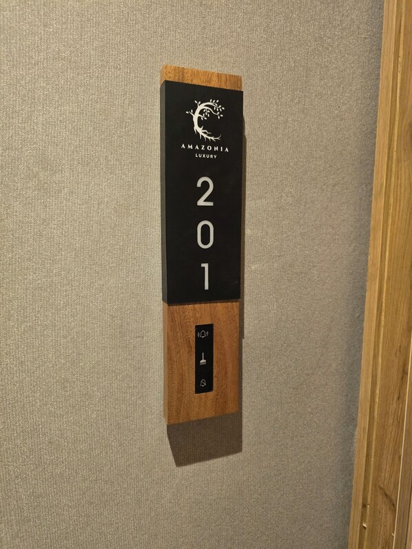 A black and wooden wall-mounted sign with 'AMAZONIA LUXURY' and the year '201' on a textured wall. - Amazonia Luxury  (Abuja)