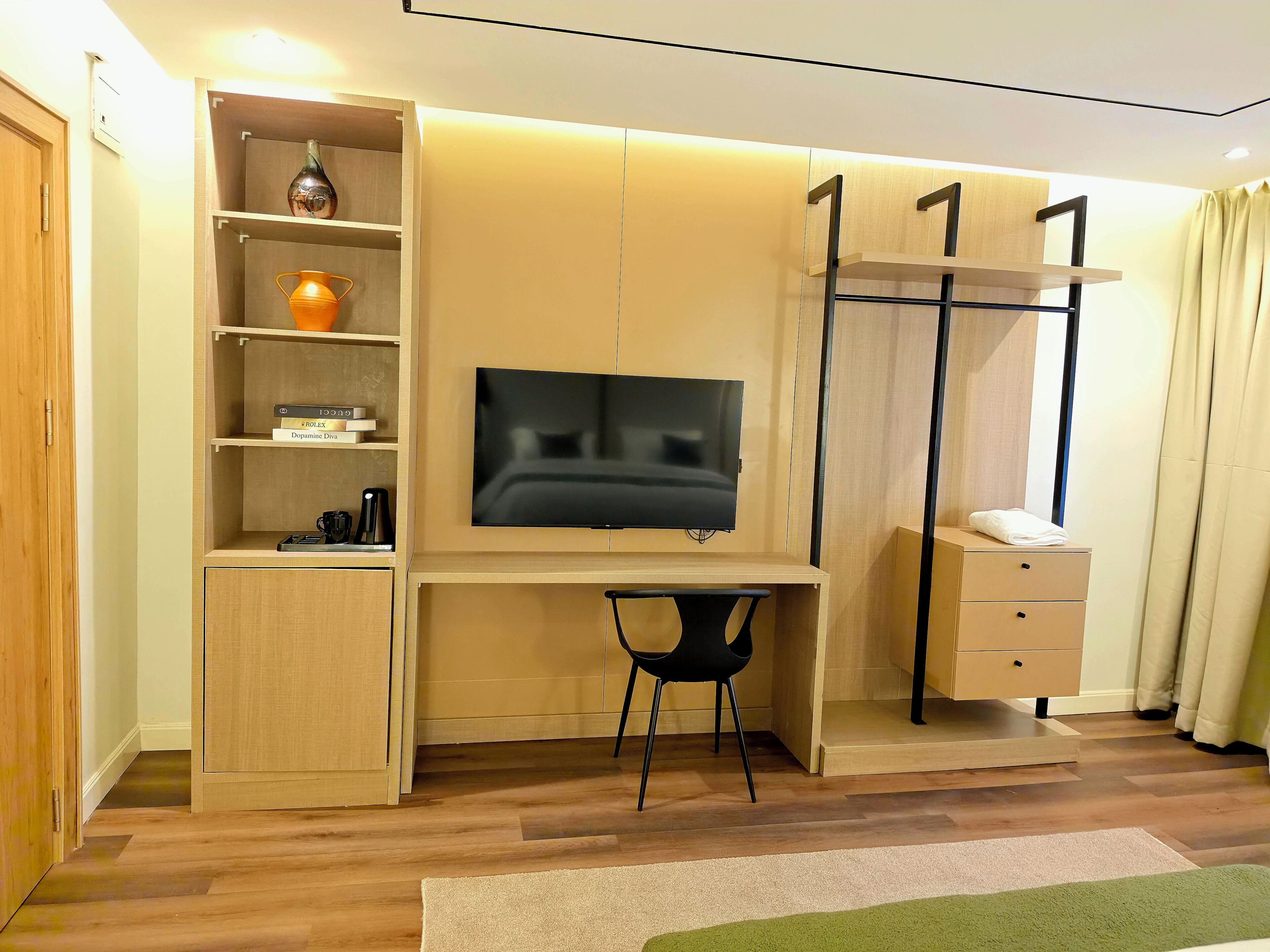 A modern room with a built-in desk, a flat-screen TV, a bookshelf, and a wardrobe.