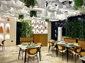 A modern dining area with marble flooring, wooden chairs, and tables set for dining. - Amazonia Luxury  (Abuja)
