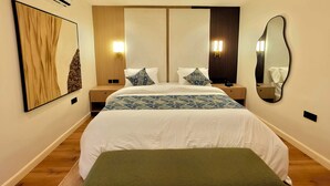 A hotel room with a large bed, bedside tables, a wall-mounted mirror, and a wall-mounted air conditioner. - Amazonia Luxury  (Abuja)