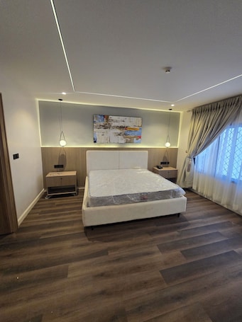 A modern bedroom with a large bed, bedside tables, a ceiling light, and a painting.. Amazonia Luxury