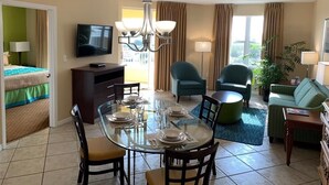 A hotel room with a dining table set for four, a television, a sofa, and a chair. - "Luxury and Comfort in Miami: for Family Holidays, in front of Sawgrass Mills". (Weston)