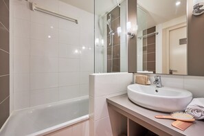 A modern bathroom with a bathtub, a sink, a mirror, and a towel rack. - Coastal Chalet for 6 With Pool (Courseulles-sur-Mer)