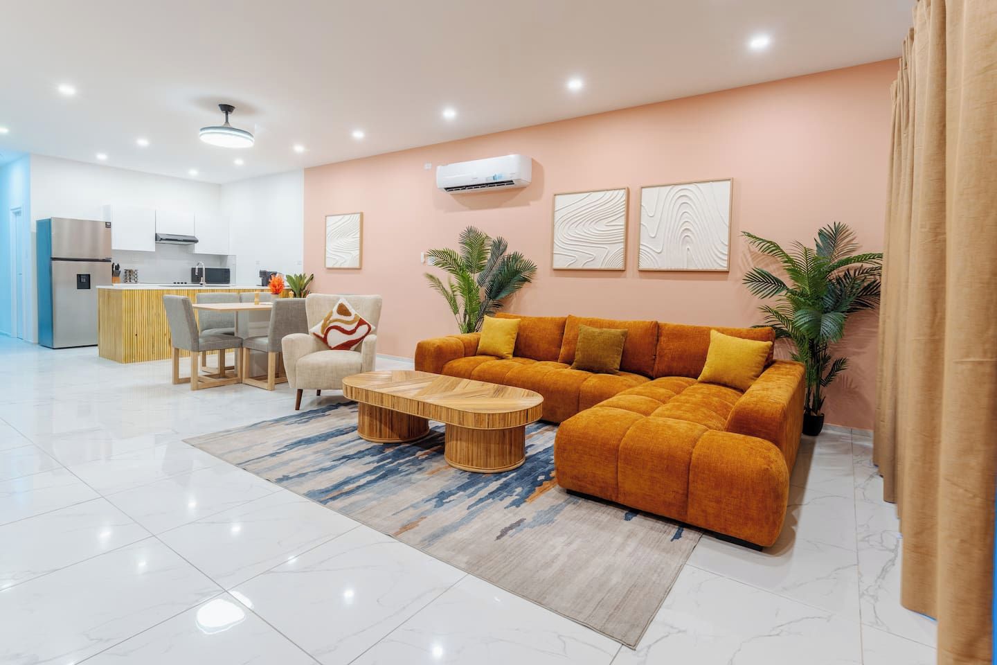 A modern living room with a sofa, coffee table, and a dining area with chairs and a table.