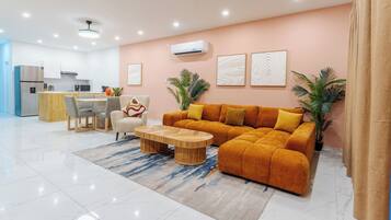 A modern living room with a sofa, coffee table, and a dining area with chairs and a table.