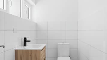 Une salle de bain moderne avec des carreaux blancs, un meuble-lavabo en bois, des toilettes blanches et un robinet noir.