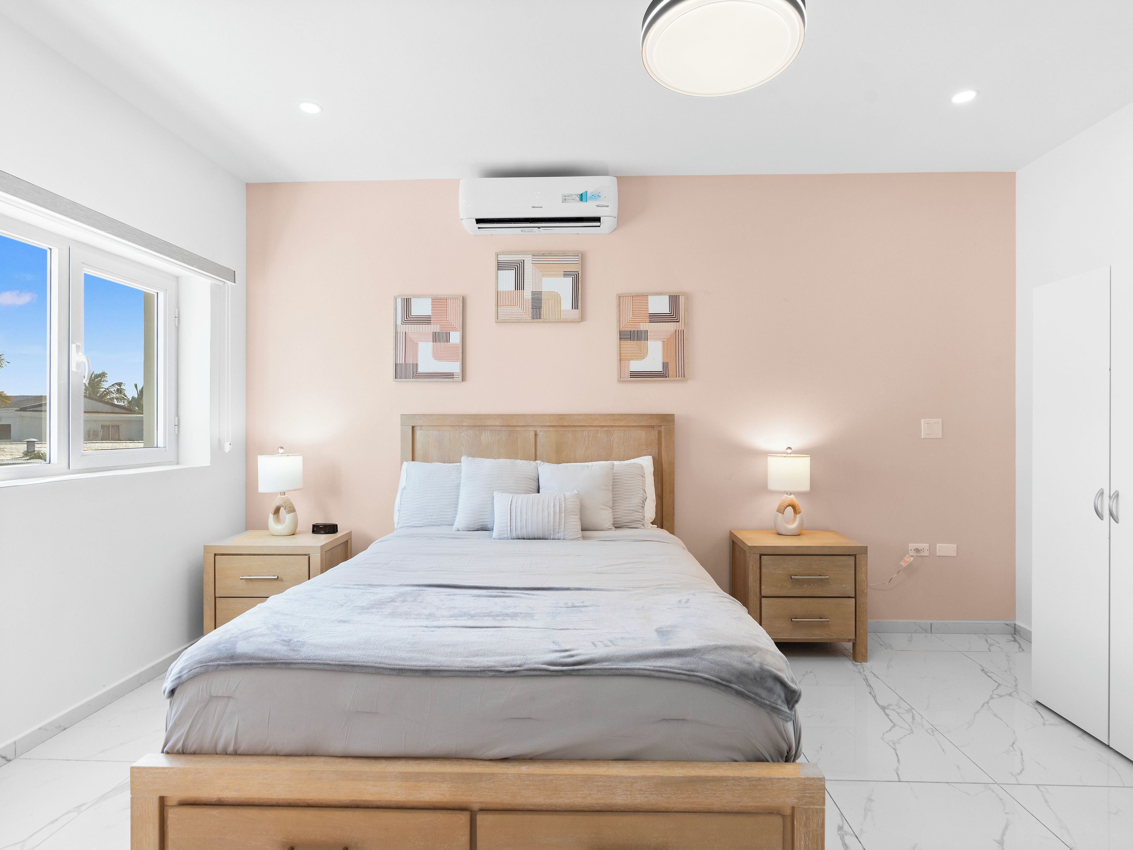 Una camera da letto con un letto, comodini, decorazioni a parete, un condizionatore d'aria e una finestra.