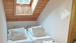 A small, cozy room with two beds, a skylight, and wooden beams on the ceiling. - 1st-floor apartment+2 private parking spaces.large, peaceful balcony. (Le Monêtier-les-Bains)