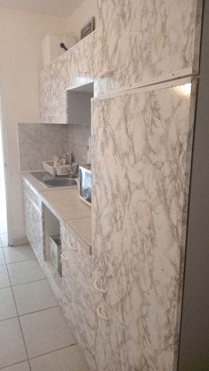 A kitchen with marble countertops, a built-in oven, and a dishwasher. - WEAVING MILL ARUBA HOSTEL (Oranjestad)