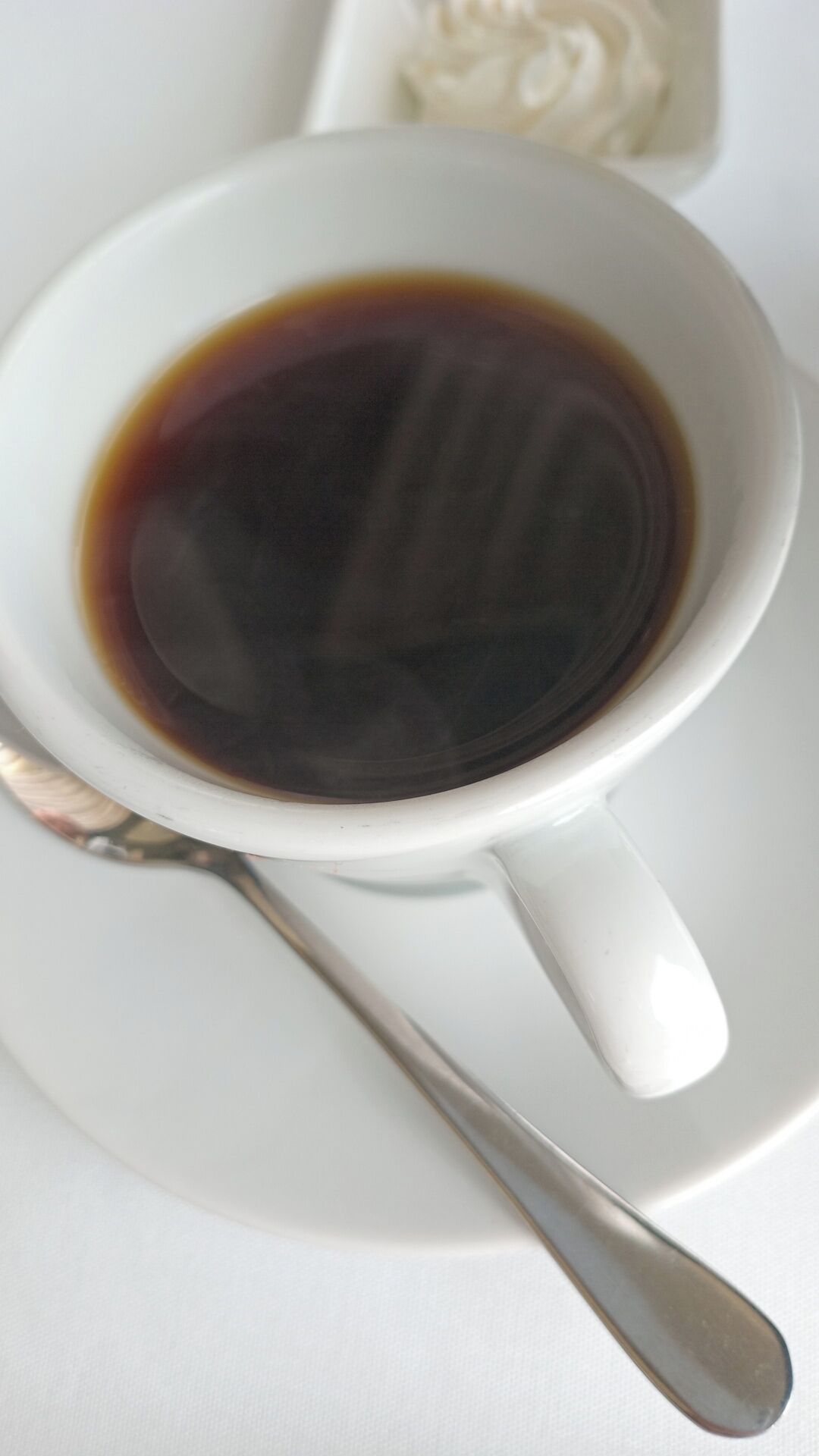 Una taza blanca de café con una cuchara sobre un platito.