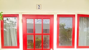 Una puerta roja con el número 2 encima, una ventana de cristal y un lazo azul en el pomo.