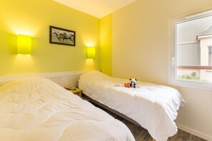 Ett hotellrum med två sängar, ett fönster med utsikt och väggmonterade lampor.